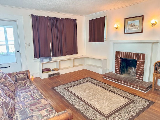 living room featuring a fireplace, crown molding, wood-type flooring, and a textured ceiling