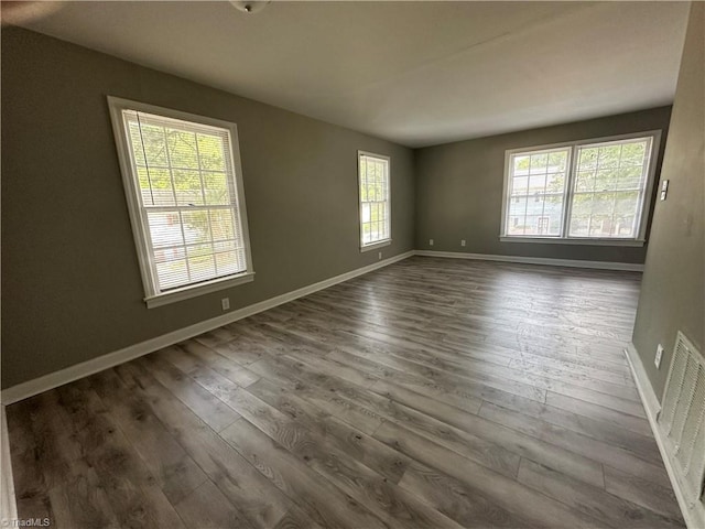 unfurnished room featuring a wealth of natural light and dark wood-type flooring