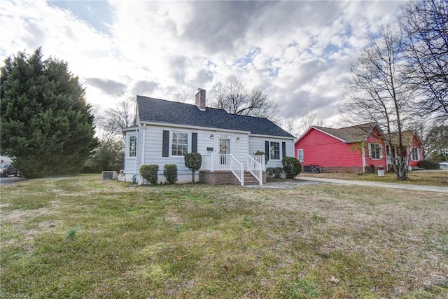 view of front of property with a front lawn, roof with shingles, and a chimney