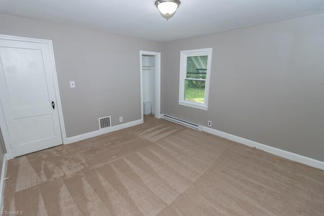 unfurnished room featuring a baseboard heating unit and light colored carpet