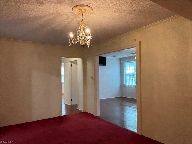 empty room featuring ornamental molding, a textured ceiling, hardwood / wood-style flooring, and a chandelier