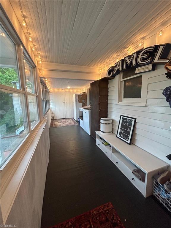 mudroom featuring wooden ceiling, wooden walls, and dark wood finished floors