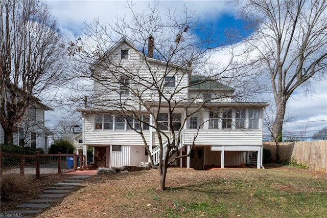 back of property featuring a sunroom, fence, a chimney, and stairs