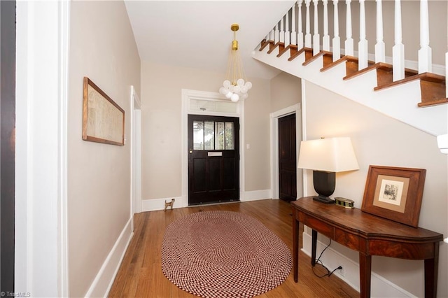 foyer with baseboards, a chandelier, and wood finished floors