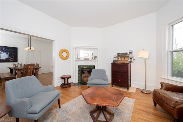 living room with light wood-style flooring, baseboards, and a fireplace with flush hearth