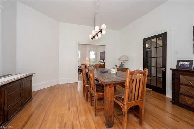 dining area featuring light wood-type flooring, baseboards, and a chandelier