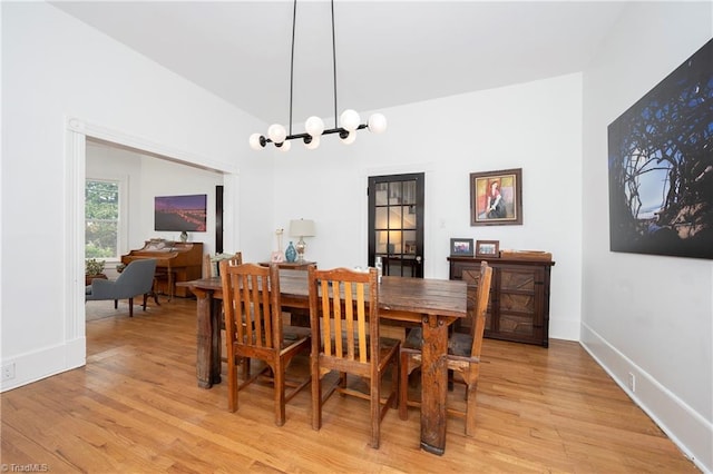 dining area featuring lofted ceiling, an inviting chandelier, baseboards, and light wood-style floors