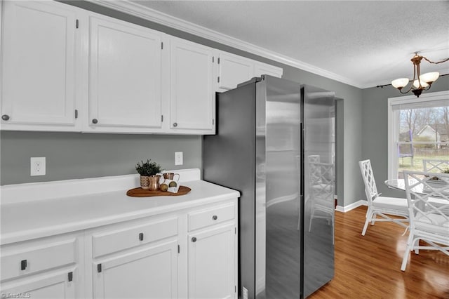 kitchen featuring an inviting chandelier, freestanding refrigerator, light countertops, white cabinets, and a textured ceiling