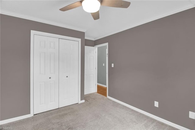 unfurnished bedroom featuring a closet, baseboards, carpet floors, and crown molding