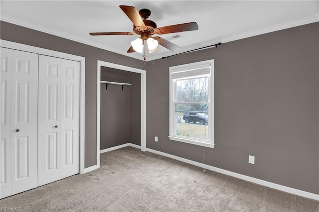 unfurnished bedroom with visible vents, two closets, baseboards, ornamental molding, and carpet flooring