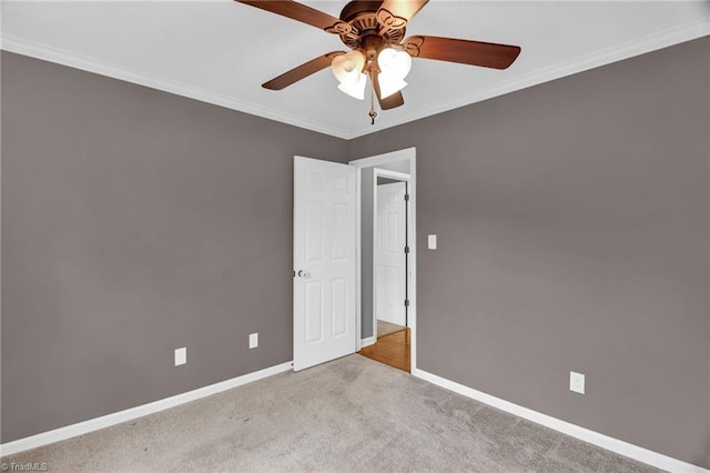 carpeted empty room featuring a ceiling fan, baseboards, and ornamental molding