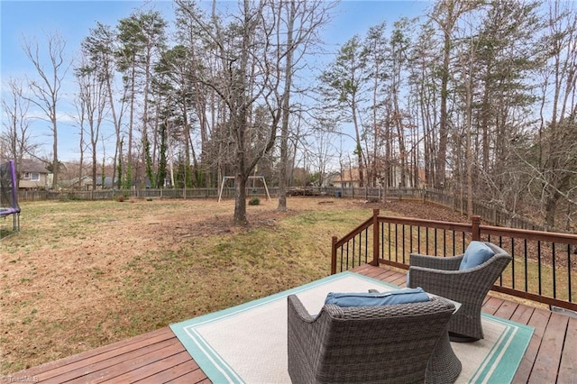 wooden deck featuring a trampoline, a fenced backyard, and a yard