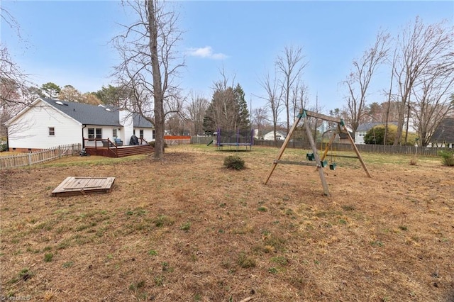 view of yard with a playground, a trampoline, a fenced backyard, and a wooden deck