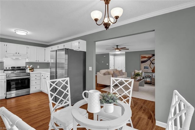 dining space with ceiling fan with notable chandelier, wood finished floors, and ornamental molding