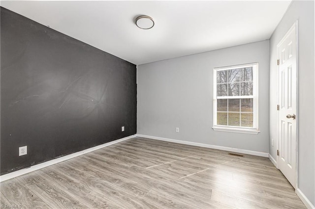 unfurnished room with visible vents, baseboards, and wood finished floors