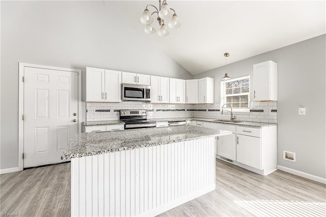 kitchen featuring white cabinets, light stone countertops, stainless steel appliances, and a sink