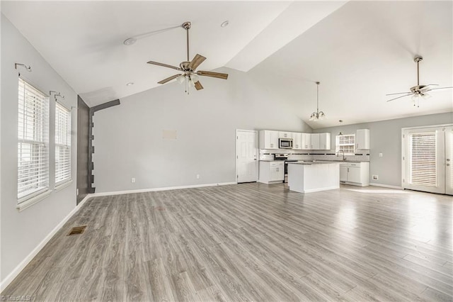 unfurnished living room featuring visible vents, baseboards, a sink, ceiling fan, and light wood-type flooring