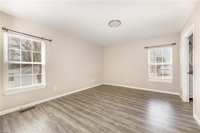 empty room featuring visible vents, baseboards, and wood finished floors