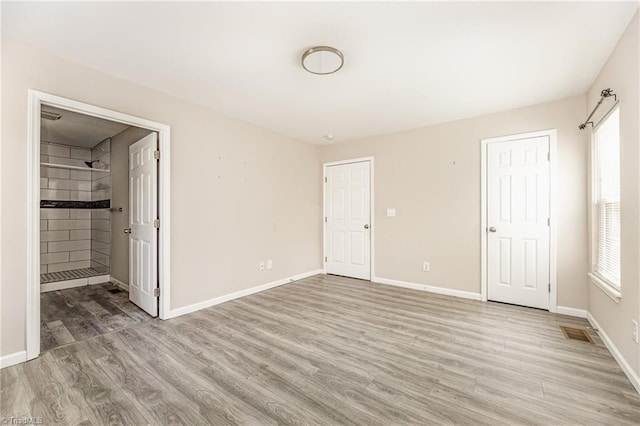 unfurnished bedroom featuring baseboards, visible vents, and light wood finished floors