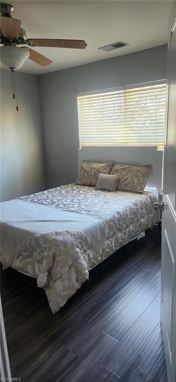 bedroom with a ceiling fan, multiple windows, wood finished floors, and visible vents