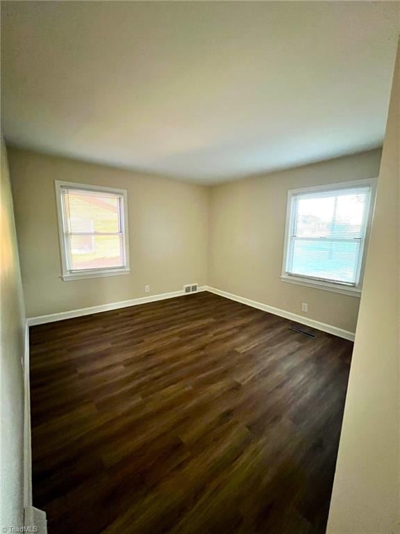 unfurnished room with dark hardwood / wood-style floors and a wealth of natural light