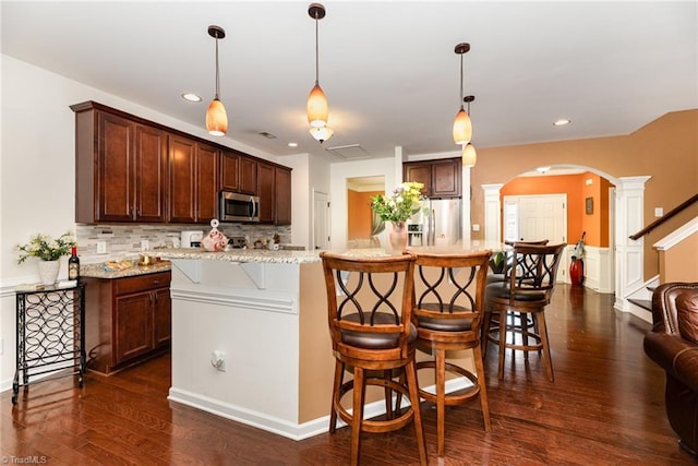 2711 Chari Park Ln, Walkertown, NC 27051 - kitchen with arched walkways, ornate columns, stainless steel appliances, a kitchen breakfast bar, and tasteful backsplash