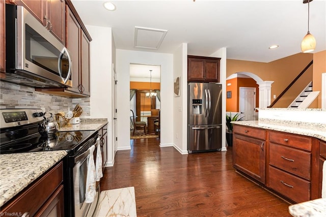 2711 Chari Park Ln, Walkertown, NC 27051 - kitchen with appliances with stainless steel finishes, arched walkways, decorative backsplash, dark wood-type flooring, and light stone counters