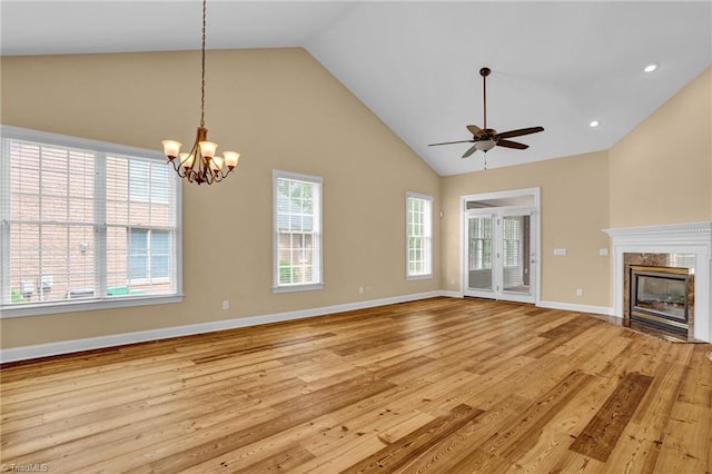 unfurnished living room with plenty of natural light, light hardwood / wood-style floors, high vaulted ceiling, and a high end fireplace