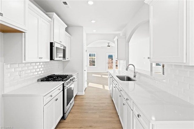 kitchen with sink, white cabinetry, light wood-type flooring, ceiling fan, and stainless steel appliances