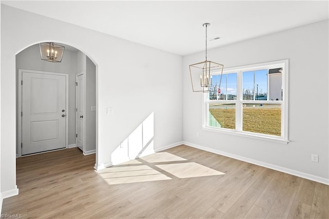 unfurnished dining area featuring light wood-type flooring and an inviting chandelier