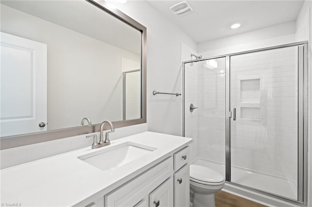 bathroom with hardwood / wood-style flooring, vanity, toilet, and a shower with shower door