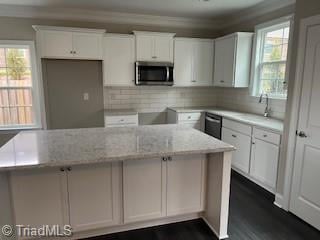 kitchen featuring decorative backsplash, white cabinetry, a healthy amount of sunlight, and light stone counters