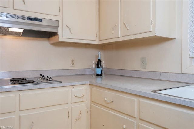 kitchen with under cabinet range hood, electric cooktop, and light countertops