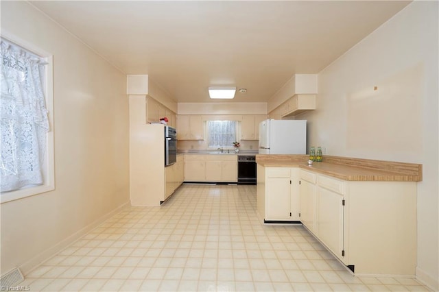 kitchen featuring baseboards, freestanding refrigerator, oven, light countertops, and dishwasher