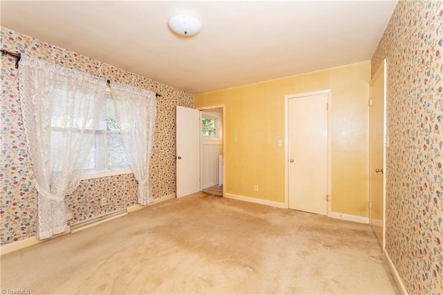 unfurnished room featuring carpet flooring, wallpapered walls, and baseboards