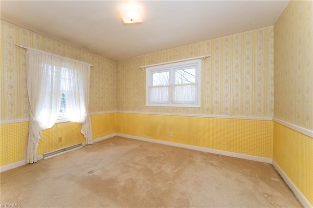 spare room with baseboards, a wainscoted wall, carpet floors, wallpapered walls, and a baseboard heating unit