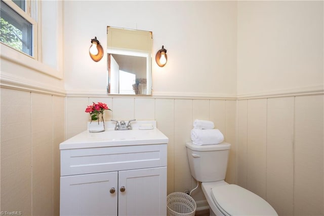 bathroom featuring vanity, wainscoting, and toilet