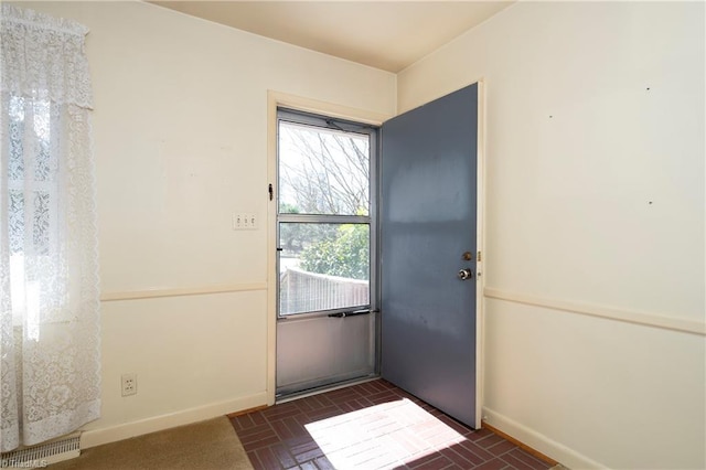 doorway featuring brick floor, baseboards, and visible vents