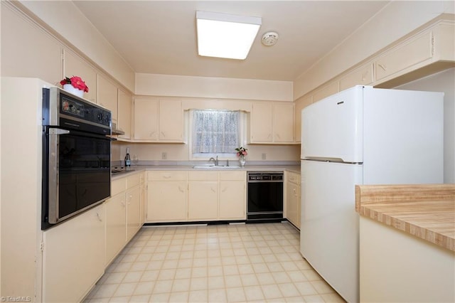 kitchen featuring freestanding refrigerator, a sink, light countertops, wall oven, and dishwasher