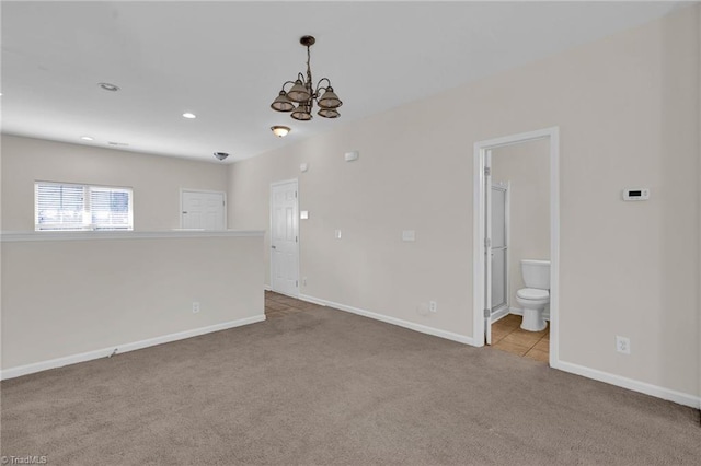 carpeted empty room featuring a chandelier