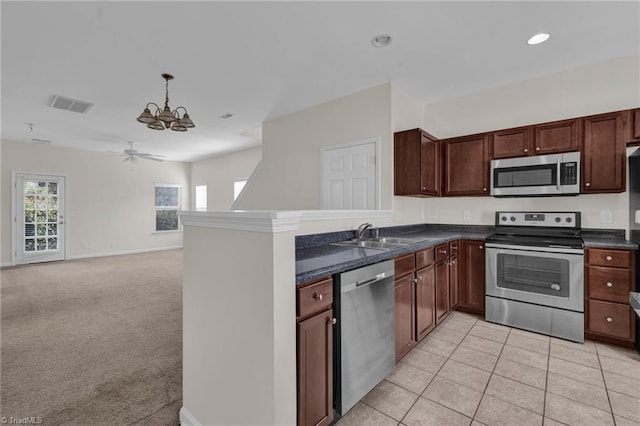 kitchen featuring sink, hanging light fixtures, stainless steel appliances, light colored carpet, and kitchen peninsula