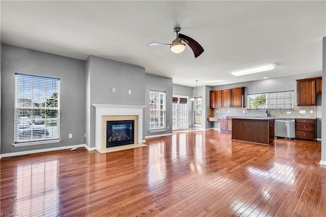 unfurnished living room with hardwood / wood-style flooring, visible vents, a fireplace, ceiling fan, and baseboards