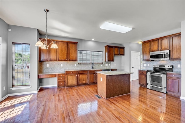 kitchen featuring brown cabinets, light wood-type flooring, backsplash, light countertops, and appliances with stainless steel finishes