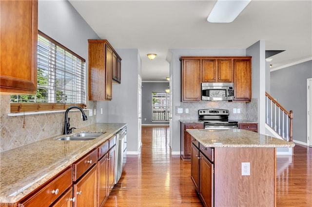 kitchen featuring baseboards, light wood-style floors, appliances with stainless steel finishes, and a sink