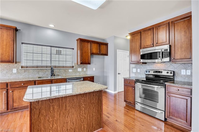 kitchen with light wood-type flooring, stainless steel appliances, and a sink