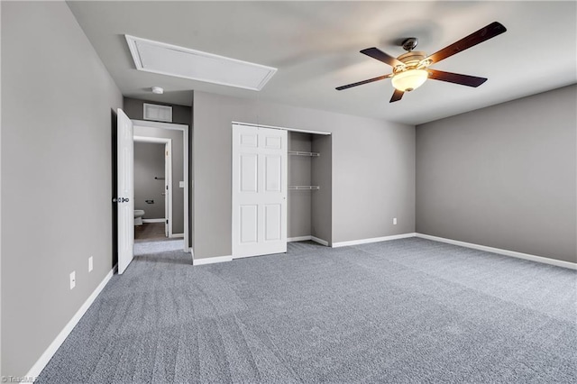 unfurnished bedroom featuring baseboards, a closet, attic access, and carpet