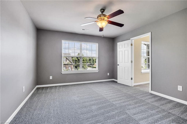 unfurnished room featuring carpet, plenty of natural light, visible vents, and ceiling fan