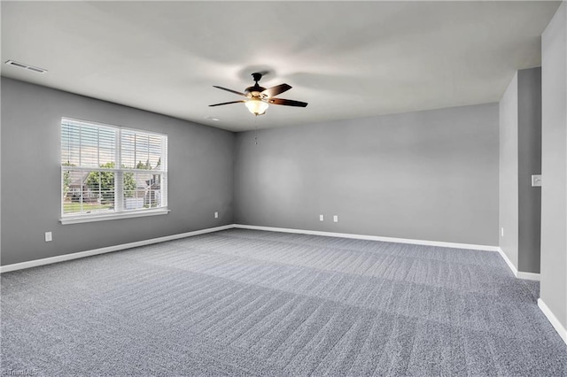 carpeted spare room featuring visible vents, baseboards, and a ceiling fan