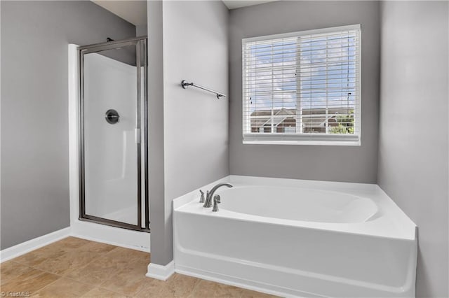 full bathroom with a garden tub, baseboards, and a shower stall
