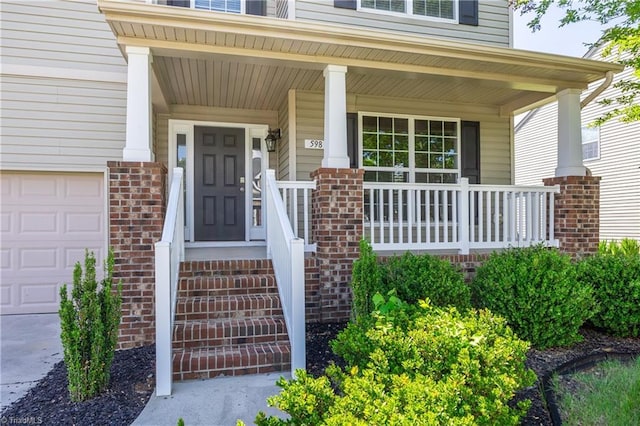 doorway to property with brick siding, covered porch, and an attached garage